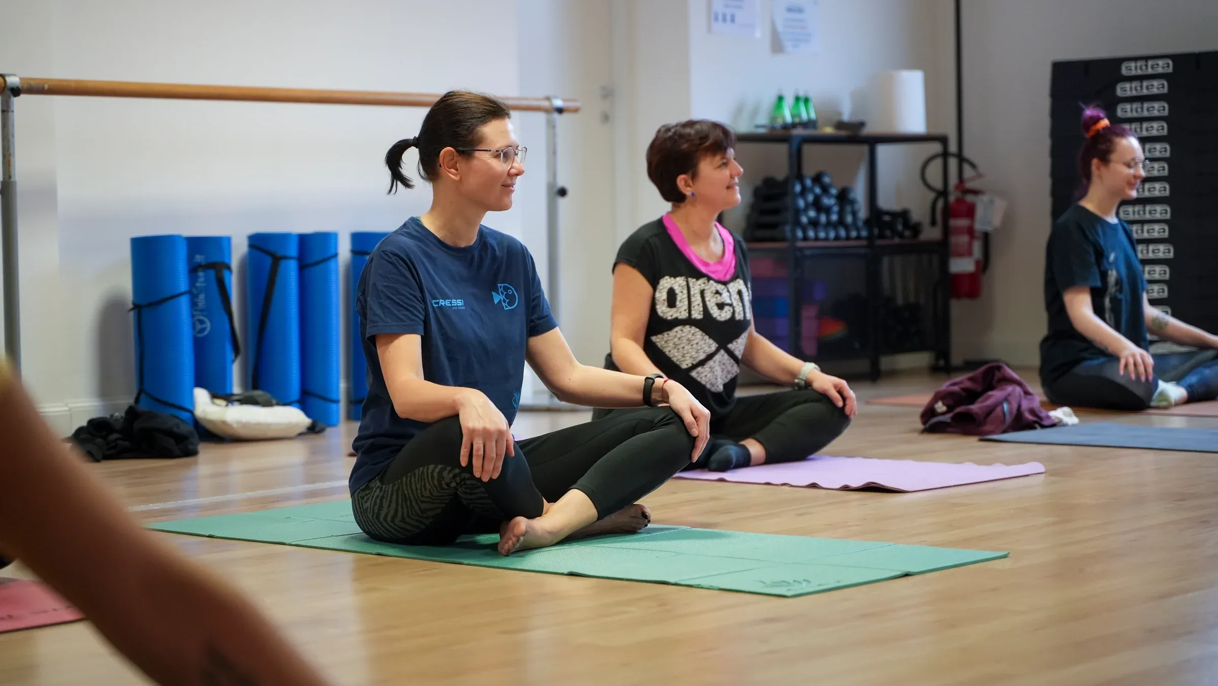 Partecipanti sedute sui tappetini durante una lezione di yoga da GiZeta Sport